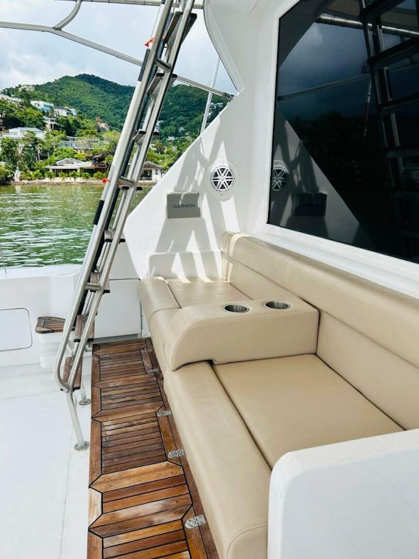 Bertram-54 1988 -Stuart-1988 Bertram 54 yacht with beige seating and wooden deck, docked by lush green hills.-4947210