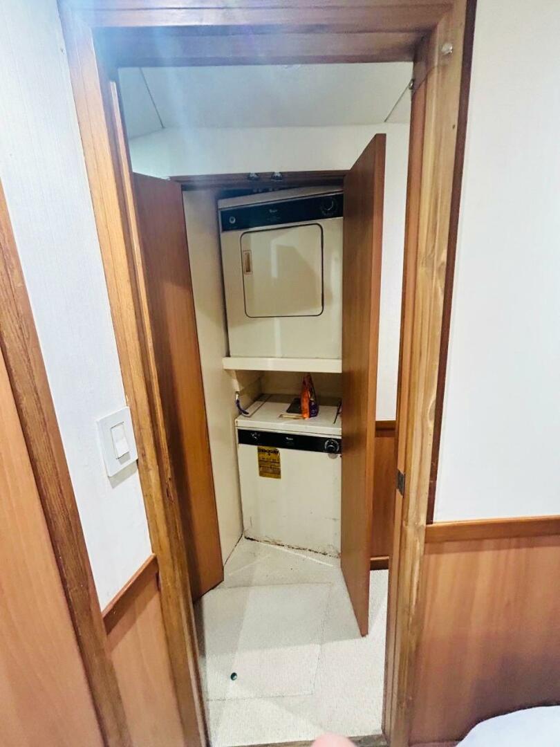 Bertram-54 1988 -Stuart-Laundry area inside 1988 Bertram 54 yacht with wood paneling and compact washer-dryer.-4947226 | Thumbnail