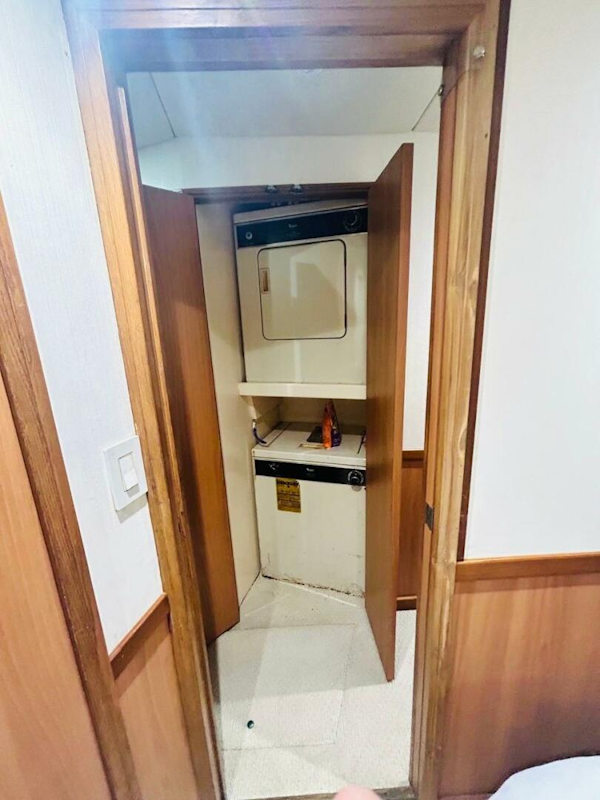 Bertram-54 1988 -Stuart-Laundry area inside 1988 Bertram 54 yacht with wood paneling and compact washer-dryer.-4947226