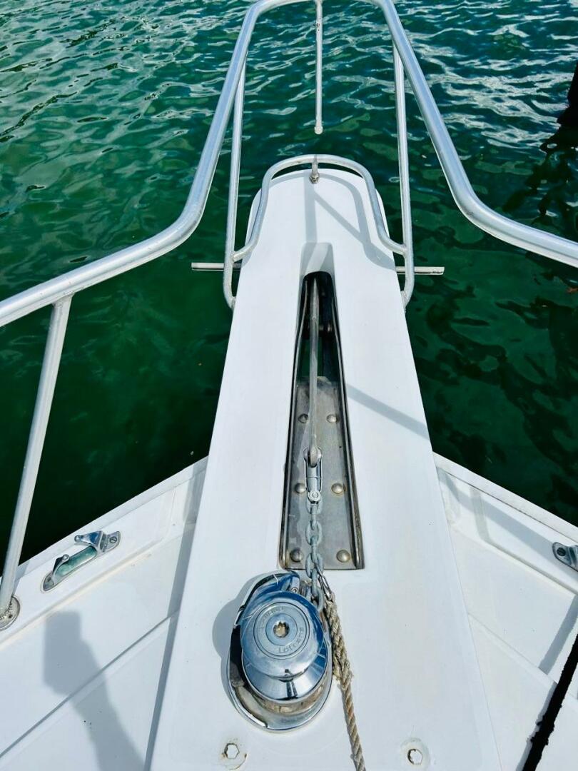 Bertram-54 1988 -Stuart-1988 Bertram 54 yacht bow with anchor chain and winch over green water.-4947237 | Thumbnail