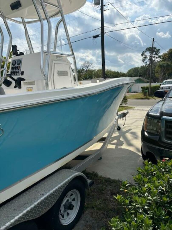 Release-208 RX 2016 -Stuart-2016 Release 208 RX boat on trailer, parked beside a black vehicle, under a partly cloudy sky.-5114917