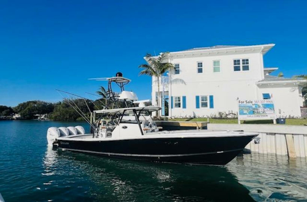 Regulator-41 2024-Fractional Ownership Available Stuart-2024 Regulator 41 boat docked by waterfront house under clear blue sky.-5234032