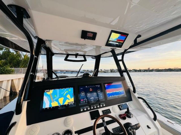 Regulator-41 2024-Fractional Ownership Available Stuart-2024 Regulator 41 boat cockpit with advanced navigation displays and steering wheel, docked by the water.-5234052